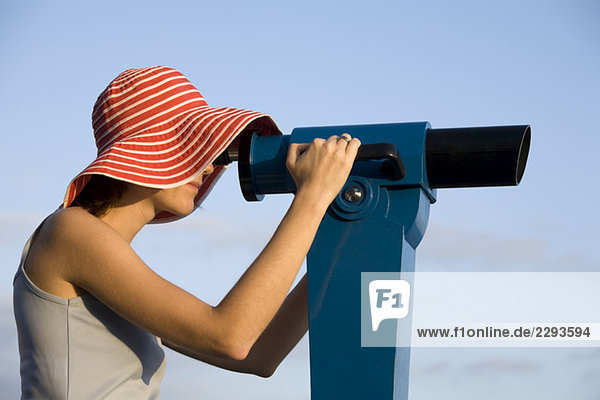 Junge Frau schaut durchs Teleskop