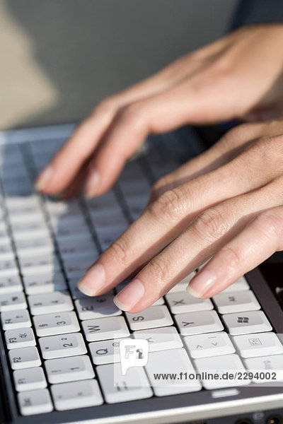 Weibliche Hand mit Tastatur des Laptops  Nahaufnahme