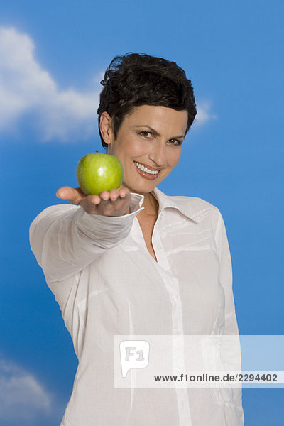 Junge Frau hält Apfel  lächelnd  Portrait