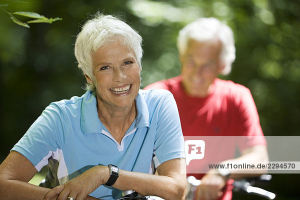 Seniorenpaar mit Fahrrädern  Frau lächelnd  Portrait