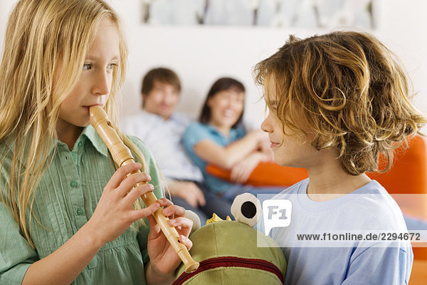Boy (6-7) and girl (8-9)  playing recorder