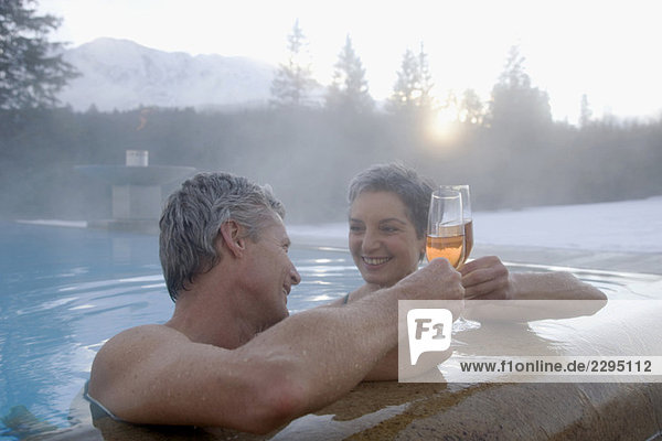 Erwachsenes Paar mit Champagner im Schwimmbad  Portrait