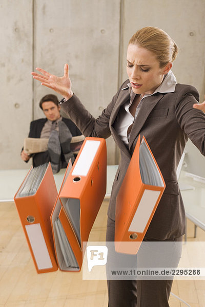 Businesswoman carrying folders  businessman in the background