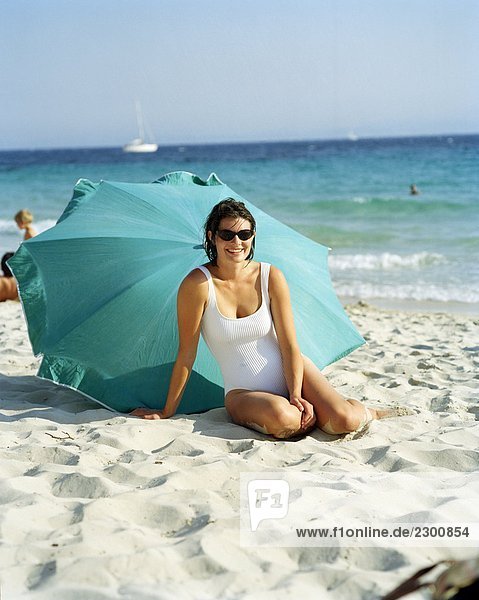 Eine skandinavische Frau sitzt vor einem Sonnenschirm Corsica
