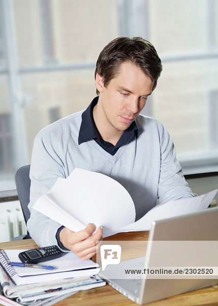 Young man browsing through documents at work