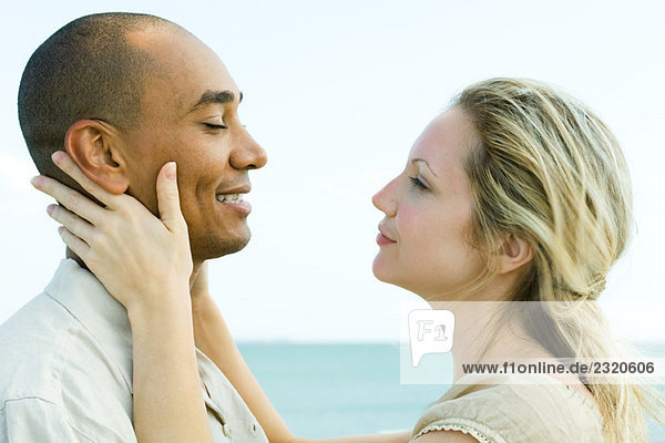 Couple face to face  woman holding man's neck  side view