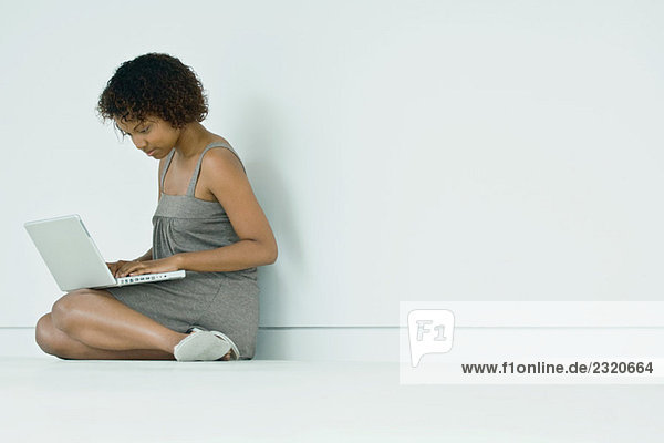 Young woman sitting on the ground  using laptop computer