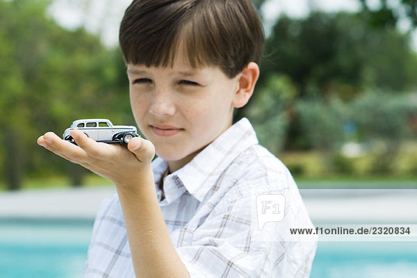 Boy holding toy car in palm of hand