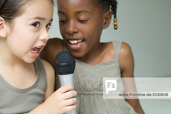 Zwei kleine Mädchen singen zusammen ins Mikrofon  Nahaufnahme