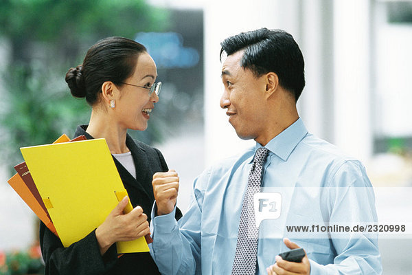Male and female business partners smiling at each other  man clenching fist