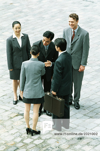 Group of professionals standing together  man and woman shaking hands  high angle view