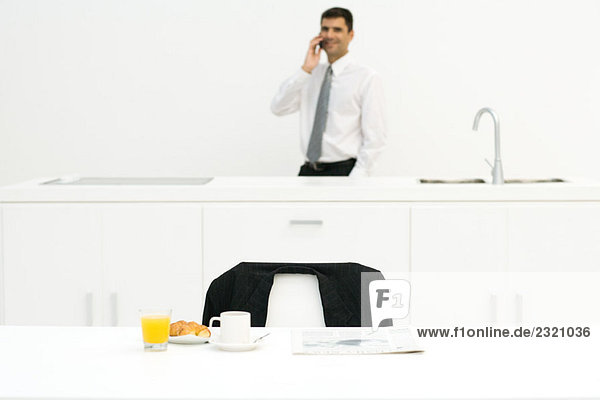 Geschäftsmann in der Küche stehend  mit dem Handy  Schwerpunkt Frühstück im Vordergrund