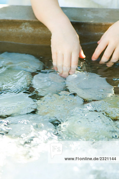 Kind berührt Felsen im flachen Pool  Blick in den Ausschnitt