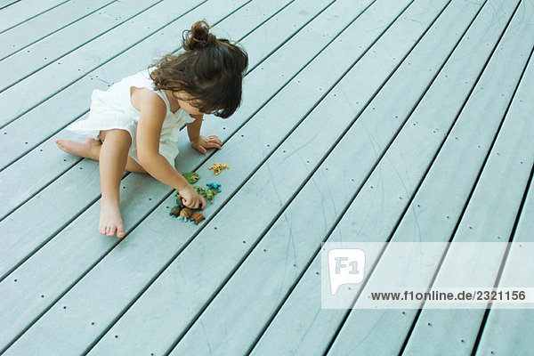 Kleines Mädchen auf Deck sitzend  mit Plastikspielzeug spielend  Hochwinkelansicht