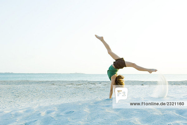 Kleines Mädchen beim Handstand am Strand  Seitenansicht