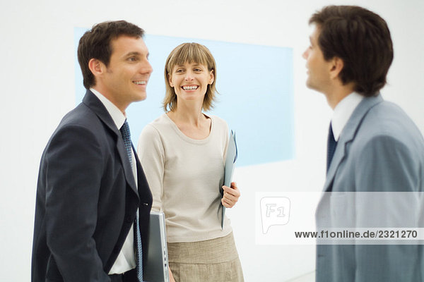Three business associates standing together  having a discussion  smiling