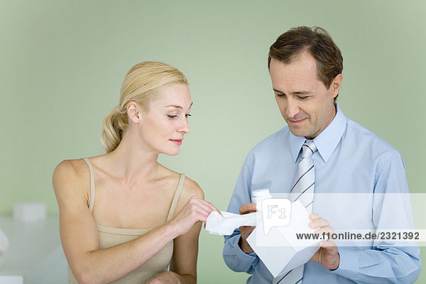 Couple standing together  man holding tissue box  woman taking tissue