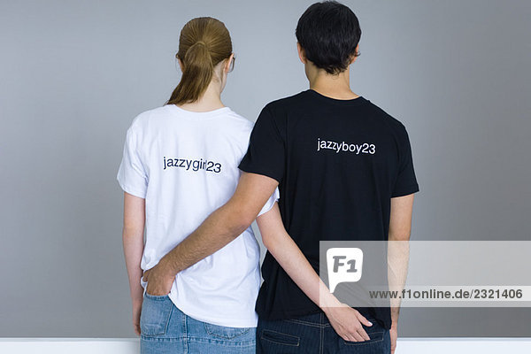 Junges Paar in individuellen T-Shirts  Arme um die Taille  Rückansicht