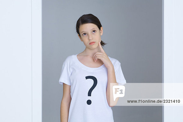 Mädchen im T-Shirt mit Fragezeichen bedruckt,  Gesicht berühren,  nach oben schauen