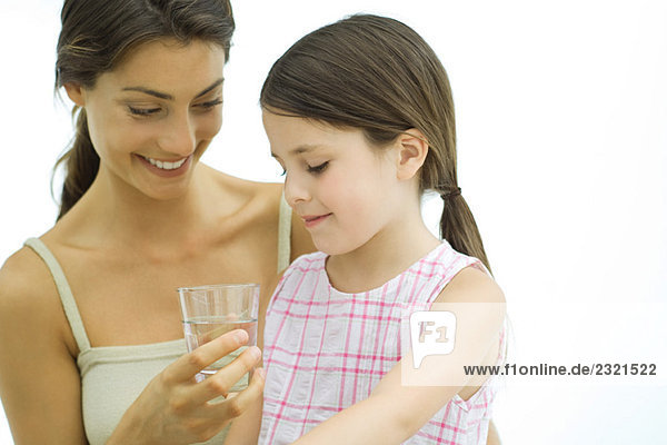 Frau hält Glas Wasser für Mädchen hoch