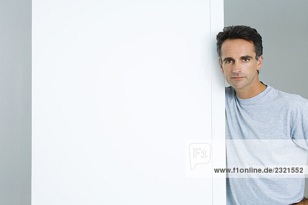 Man leaning against edge of wall  looking at camera