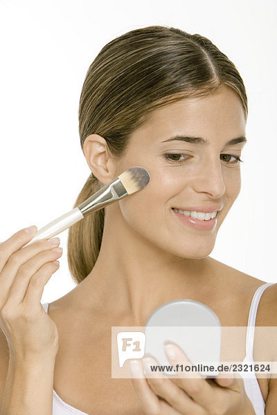 Woman applying blush  looking in hand mirror