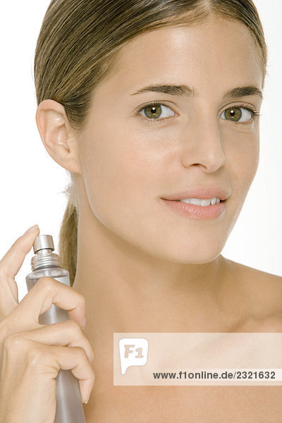 Woman putting on perfume  smiling at camera