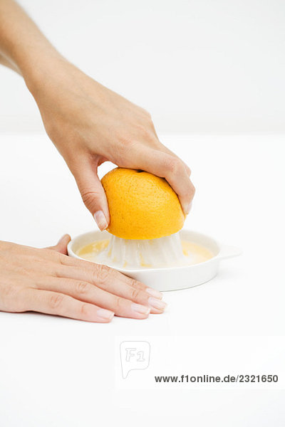 Frau quetscht Orange mit Zitruspresse  abgeschnittene Ansicht der Hände