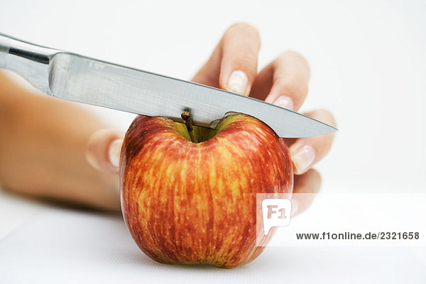 Frau schneidet Apfel mit Messer  abgeschnittene Handansicht