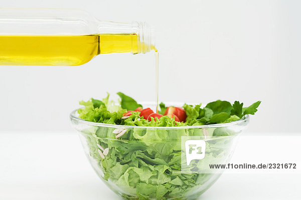 Olivenöl wird auf Salat gegossen  Nahaufnahme