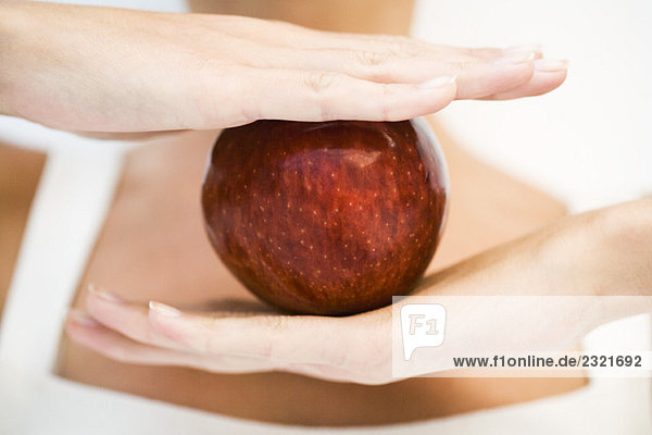 Frau hält den Apfel zwischen den Händen  Nahaufnahme  Ausschnitt