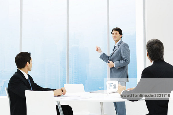 Geschäftsleute in Besprechung  ein stehendes  aus dem Fenster zeigend