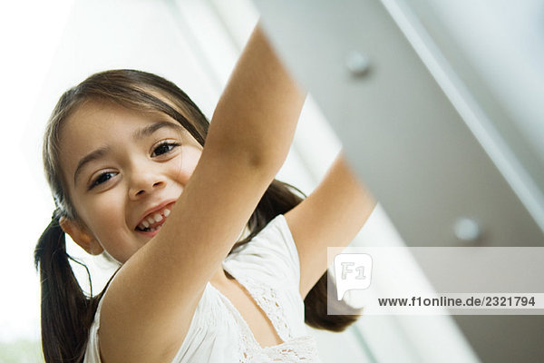 Kleines Mädchen mit Zöpfen lächelnd vor der Kamera  Arme erhoben  Portrait