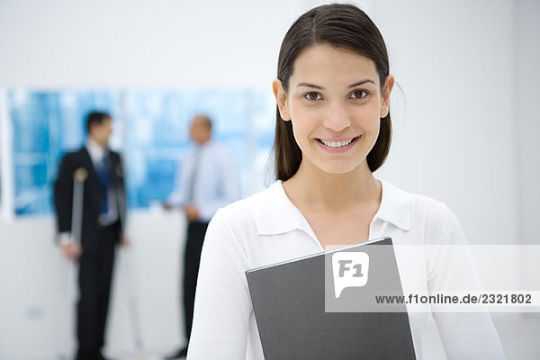 Young female office worker holding file  smiling at camera