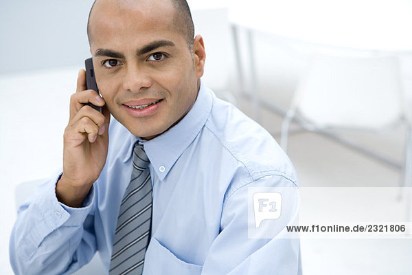 Businessman using cell phone  smiling at camera