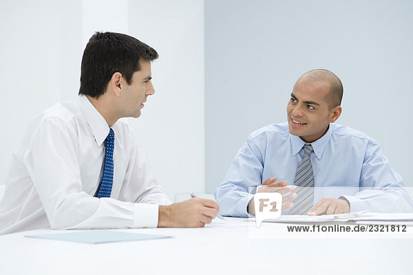 Zwei Geschäftsleute  die am Tisch sitzen und sich treffen.