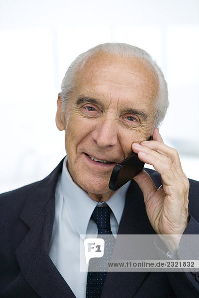 Senior businessman using cell phone  smiling  portrait