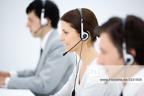 Call center  focus on woman wearing headset  smiling  side view