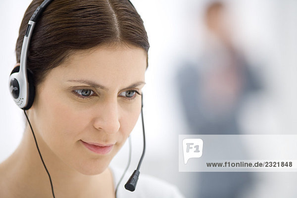 Customer service representative wearing headset  listening and looking down  close-up