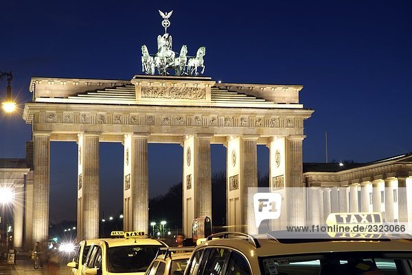 Taxis near memorial gate lit up at dusk  Brandenburg Gate  Berlin  Germany