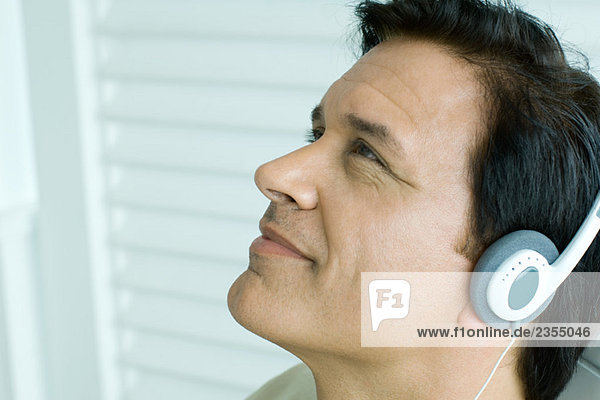 Mann hört Kopfhörer  schaut nach oben  Seitenansicht