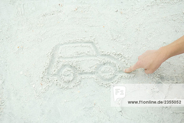Teenage boy drawing car in sand  cropped view