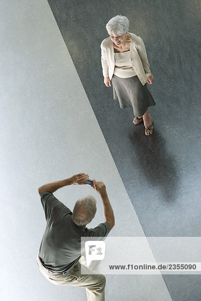 Man photographing wife with digital camera  viewed from directly above