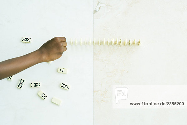 Kind stellt Dominosteine auf  abgeschnittene Ansicht der Hand
