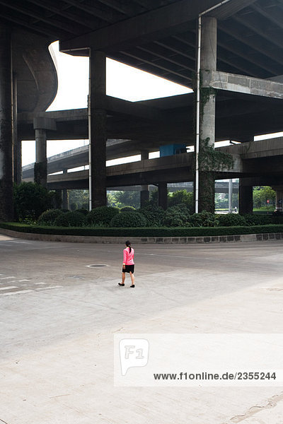 China  Guangzhou  Fußgängerin unter der Brücke  Rückansicht