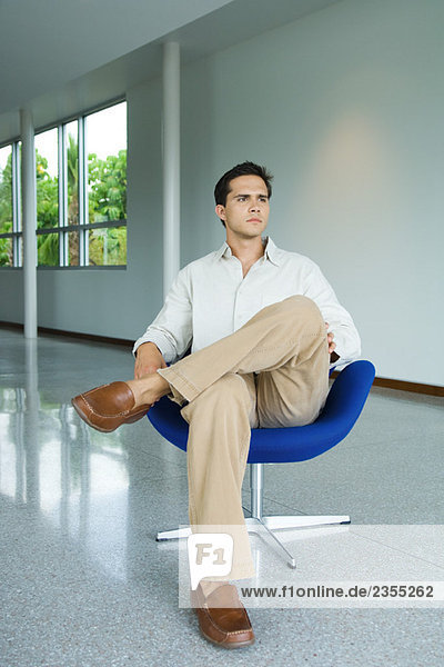 Young man sitting in chair  full length