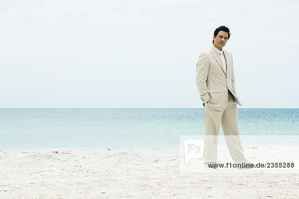 Geschäftsmann am Strand stehend mit Händen in den Taschen  volle Länge