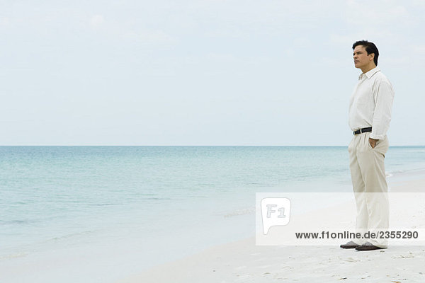 Mann am Strand stehend  mit Blick auf die Aussicht