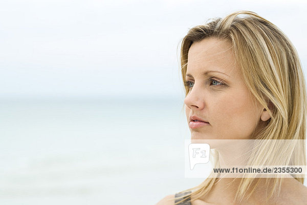Blonde Frau schaut in die Ferne  Meer im Hintergrund  Kopf und Schultern
