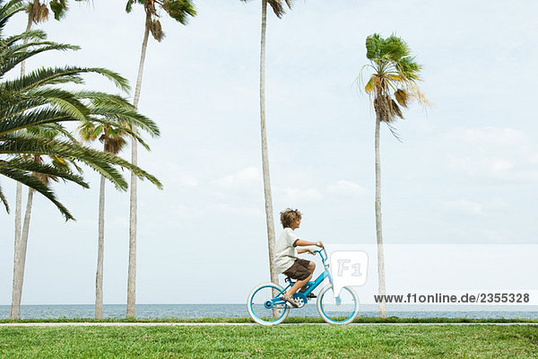 Junge mit Fahrrad am Strand  Seitenansicht